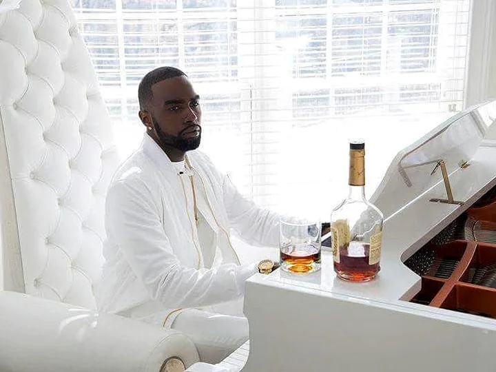 Chad Focus seated beside a white piano